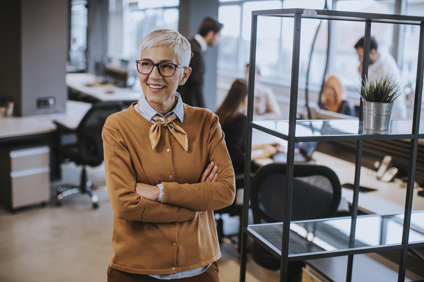 Susan standing in the office of the company she built, arms crossed, smiling