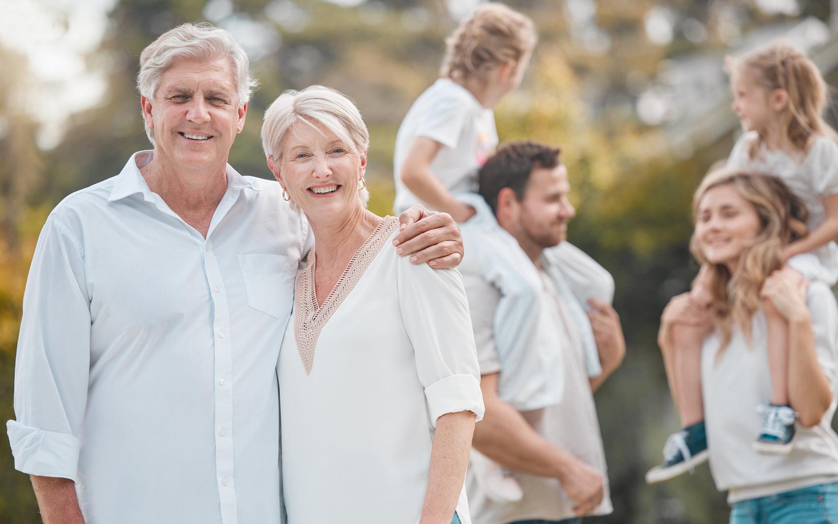 Grandparents in white, their children and grandchildren gathered in the light behind them